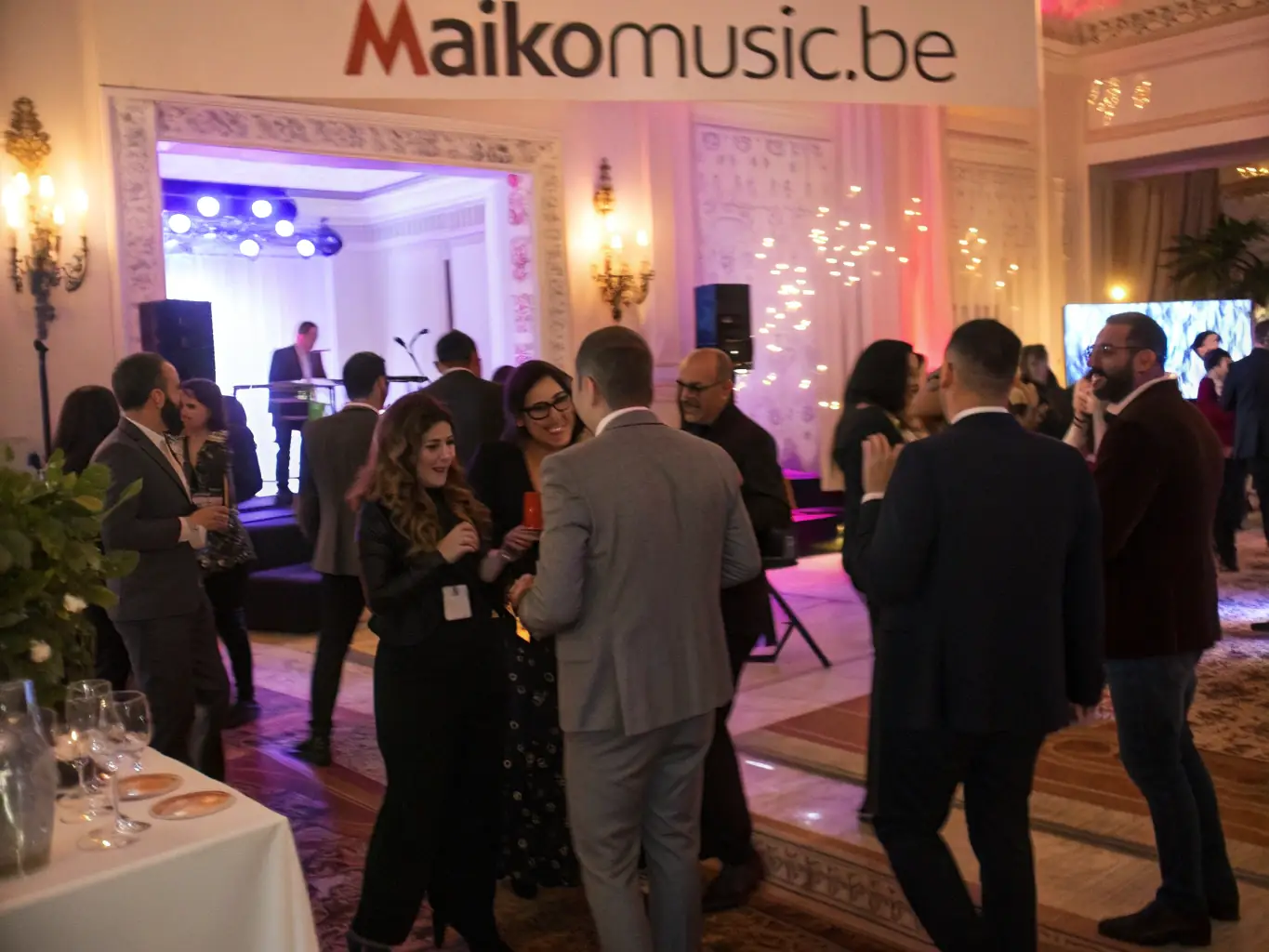 A sophisticated corporate event with a DJ providing background music, featuring professionals networking and enjoying the ambiance.